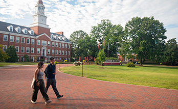 two students walking past carpenter academic center in the background